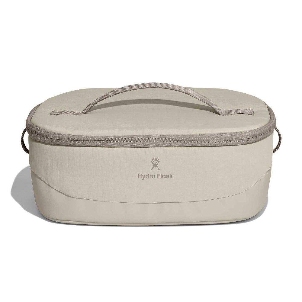 Beige Hydro Flask oval insulated bag with zip-around lid, fabric top handle, short side handles, and centered logo. Slightly structured base.
